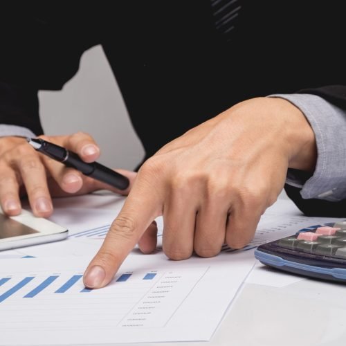 Business people discussing financial charts - closeup shot of hands over table.